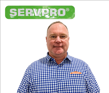 Jeff Truitt for SERVPRO photo on white wall, male employee in blue checkered shirt